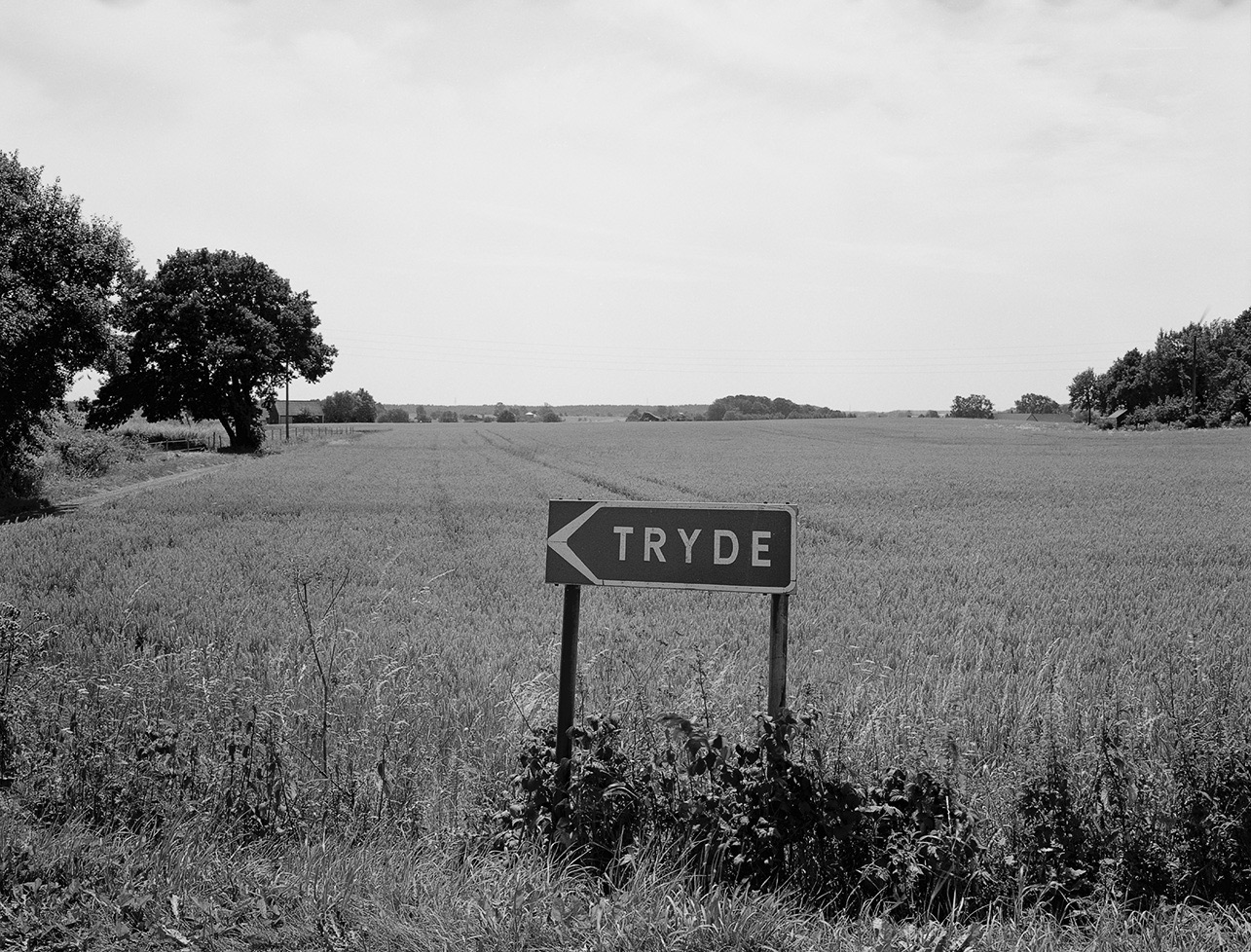 Skylt Tryde framför sädesfält